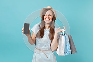 Portrait of woman in summer dress, straw hat holding packages bags with purchases after shopping, mobile cellphone with