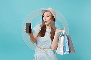 Portrait of woman in summer dress, straw hat holding packages bags with purchases after shopping, mobile cellphone with