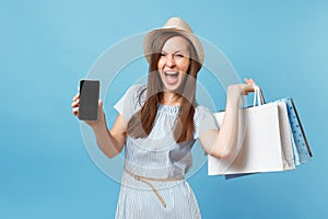 Portrait of woman in summer dress, straw hat holding packages bags with purchases after shopping, mobile cellphone with