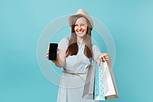 Portrait of woman in summer dress, straw hat holding packages bags with purchases after shopping, mobile cellphone with