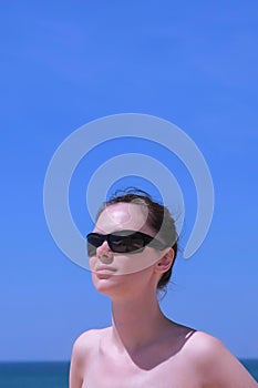 Portrait woman sunbathing stand on beach sunglasses on sea and sky background.
