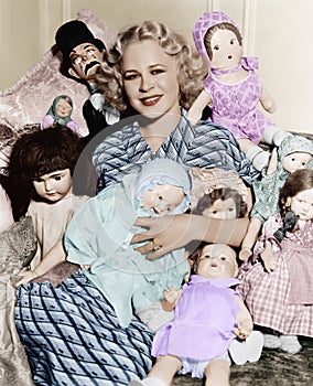 Portrait of a woman surrounded by dolls and smiling