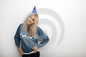 Portrait of woman in sweater wearing party hat against white background