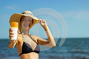 Portrait of woman taking skincare with sunscreen lotion at beach