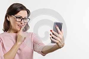 Portrait of a woman tells secrets and gossip on the cell phone. Background white, studio, copy space