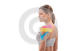 Portrait of woman with therapeutic tape for shoulder pain, aches and tension. It is also used for prevention and