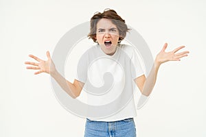 Portrait of woman throwing tantrum, shouting and screaming, shaking hands and yelling outraged, standing over white