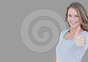 Portrait of woman with thumbs up with grey background