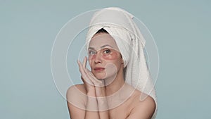 Portrait of a woman with a towel on her head and red hydrogel patches under her eyes close up. A woman enjoys the purity