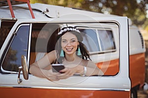 Portrait of woman using mobile phone while leaning on door