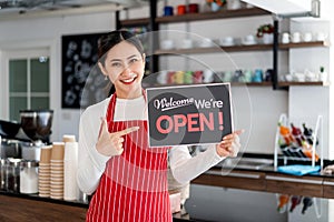 Portrait of woman waitress standing at her coffee shop gate