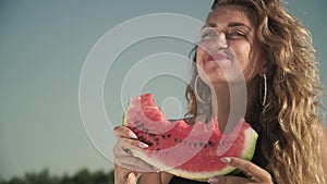 Portrait of woman with waving hair eating watermelon outdoors Lovely girl enjoys her rest and smiles