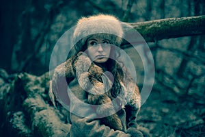 Portrait of a woman wearing fur hat and fox fur pelt on her shoulders.Shot in forest surroundings.