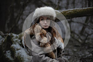 Portrait of a woman wearing fur hat and fox fur pelt on her shoulders.Shot in forest surroundings.