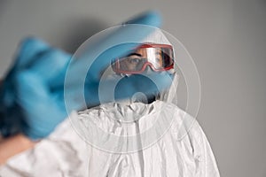 Portrait of woman wearing lab coat, nitrile gloves, goggles, face mask and NBC protective suit for covid-19 coronavirus, posing