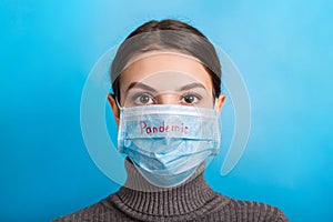 Portrait of a woman wearing medical mask with pandemic word at blue background. and healthcare concept