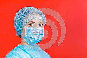 Portrait of a woman wearing medical uniform and mask with epidemic word at red background. concept. Respiratory