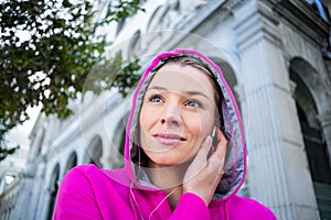 Portrait of a woman wearing a pink jacket putting her headphones