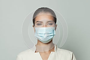 Portrait of woman wearing protective medical face mask on white background. Medicine, cosmetology and vaccination concept