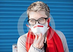 Portrait of Woman wearing white and red face mask and red scarf against blue background