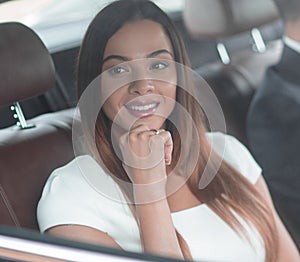 Portrait of a woman in a white dress in her car in the back seat