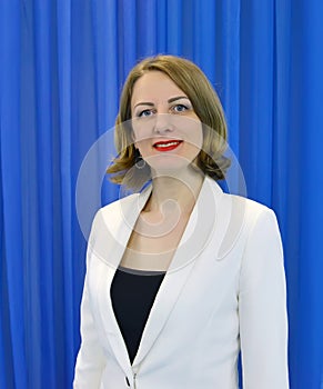 Portrait of a woman in a white jacket against a blue background