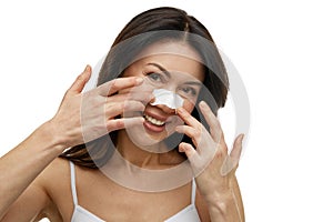 Portrait of woman with white patch for cleansing skin pores from impurities against white studio background.