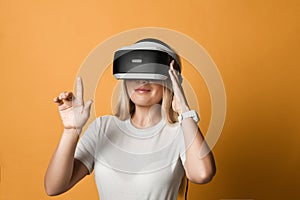 Portrait of woman in white t-shirt using VR glasses exploring augmented reality touching virtual things pressing buttons
