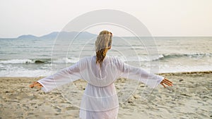 Portrait woman in a white tunic shirt on beach, near stormy sea.