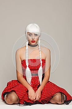 Portrait of a woman in a white wig, red dress and sneakers. Studio photo session