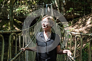 Portrait of a woman at a wooden suspension bridge over a small creek valley in the woods