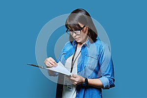 Portrait of woman worker with industrial center card clipboard, on blue background