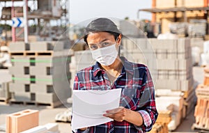 Portrait of woman worker in mask standing with note list at warehouse