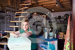 Portrait Of Woman In Workshop Upcycling And Working On Furniture With Sandpaper