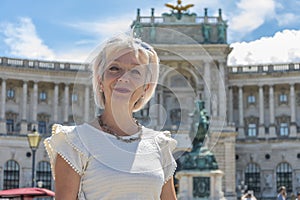 Portrait of a woman 60-65 years old in summer against a blurred background of ancient architecture of the Austrian city of Vienna