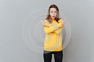 Portrait of a woman in yellow sweater pointing fingers away