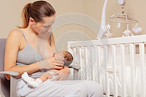 Mother breastfeed newborn infant baby sitting on the chair photo
