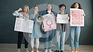 Portrait of women feminists holding gender equality posters and screaming in megaphone