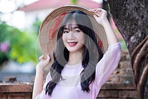 Portrait women in pink ao dai Vietnam and holding straw hats