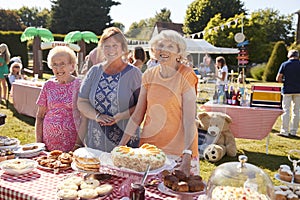 Portrait Of Women Serving On Cake Stall At Busy Summer Garden Fete photo