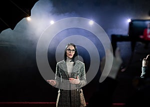 Portrait of women speaking through a microphone in dark conference hall. woman talks into microphones at press