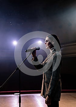 Portrait of women speaking through a microphone in dark conference hall. woman talks into microphones at press