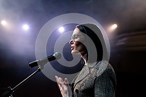 Portrait of women speaking through a microphone in dark conference hall. woman talks into microphones at press