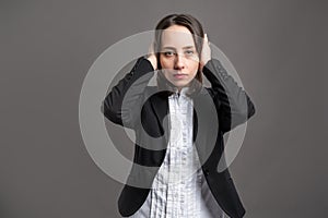 Portrait of wonderful young business woman covering ears like deaf concept, poseing on isolated gray background