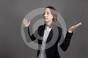 Portrait of wonderful young business woman with open arms looking up, side view, poseing on isolated gray background