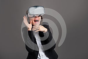 Portrait of wonderful young business woman wearing virtual reality VR glasses, poseing on isolated gray background