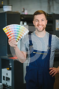 Portrait of worker at control room checking print quality at printing house.