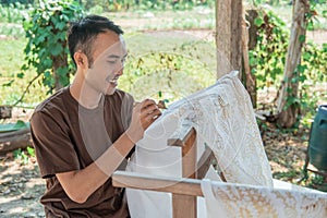 Portrait of a worker drawing batik pattern