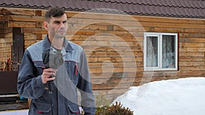 Portrait of the worker of the house which is carrying out an inspection by the thermal imager. To look for losses of