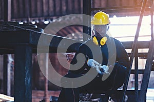 Portrait worker man with yellow helmet and ear protection in factory, Dark tone